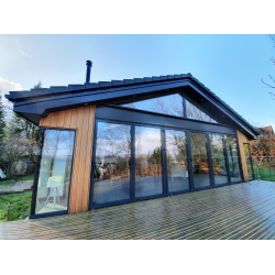 Bi-folding aluminium frame doors, with fixed triangular glazing above. Cedar cladding to the walls.